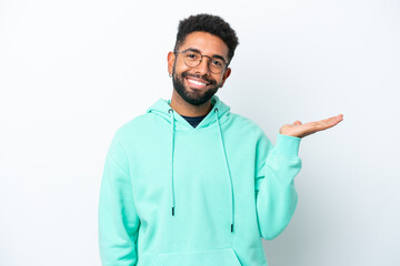 Young Brazilian man isolated on white background holding copyspace imaginary on the palm to insert an ad