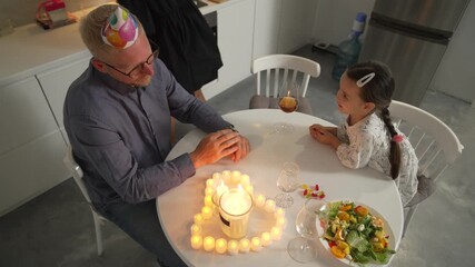 Birthday Cake Father Daughter Home Celebration: Intimate family birthday celebration at home, featuring a father and daughter with a heart-shaped candlelit cake.