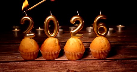 Cupcakes with candles forming 2026 glow softly on a rustic wooden table, symbolizing the start of a new year full of hope and celebration. - Powered by Adobe