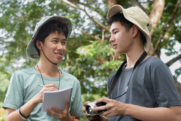 Two young researchers discuss a photo on a digital camera and compare it with the notes written in a notebook during their field study.