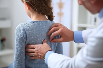 Orthopedic doctor assessing child s spine in clinic detailed view Scoliosis care