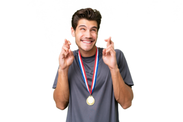 Young caucasian man with medals over isolated background with fingers crossing