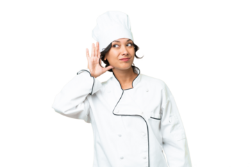 Young chef Argentinian woman over isolated background listening to something by putting hand on the ear