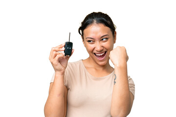 Young Uruguayan woman holding car keys over isolated chroma key background celebrating a victory