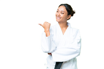 Young Uruguayan woman doing karate over isolated chroma key background pointing to the side to present a product
