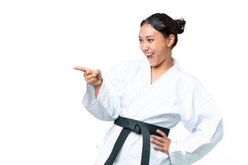 Young Uruguayan woman doing karate over isolated chroma key background pointing finger to the side and presenting a product