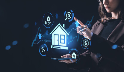 Woman interacting with futuristic real estate hologram interface concept showing house, financial icons, and digital analytics on dark background.