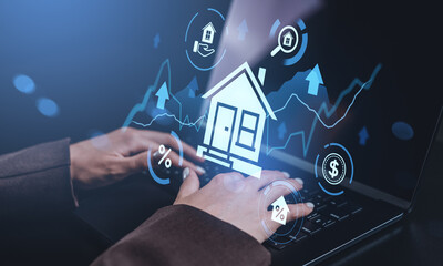 Hands typing on laptop with holographic real estate and finance icons representing digital housing...