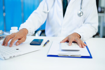 Healthcare costs and fees concept.Hand of smart doctor used a calculator and smartphone, tablet for medical costs at hospital