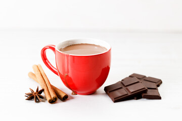 Hot chocolate in red cup on white wooden table background.