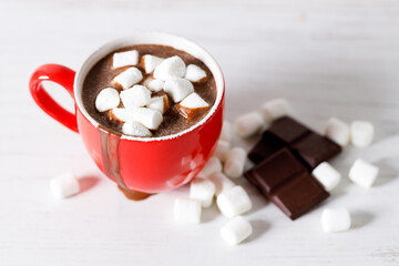 Hot chocolate in red cup on white wooden table background.