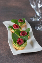 Tartlets in shape of roses with sausage, cucumber, cheese and spinach, festive snack