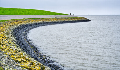 Cyclists enjoying a scenic ride along the green dike overlooking the north sea in carolinensiel, germany