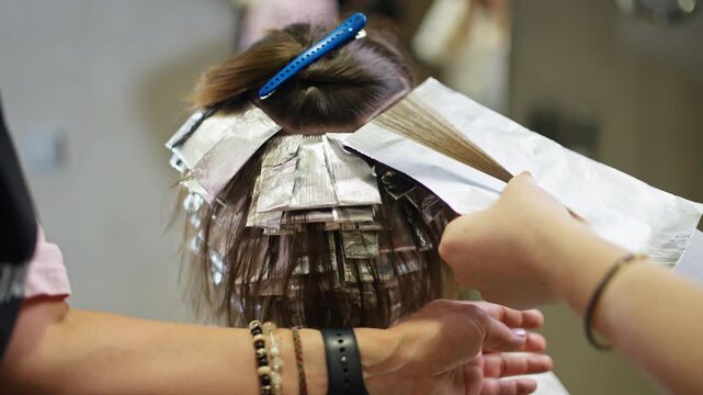 Hairdresser applying hair color to woman hair in salon interior showing professional beauty service hairstyle transformation and hair care for elegant feminine style