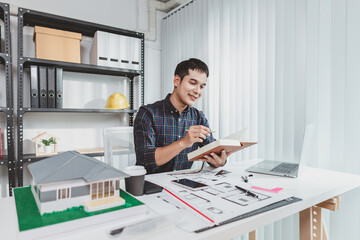 Young architect working in office with building models and floor plans, analyzing details and creating innovative design concepts, showing creativity, focus, and dedication in architecture projects.