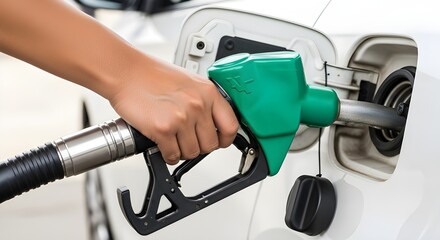 Hand holding green fuel pump nozzle filling gasoline into white car tank