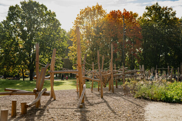 Fototapeta premium Modern wooden playground climbing structure with rope elements in public park surrounded by trees designed for outdoor recreation physical activity and safe child development