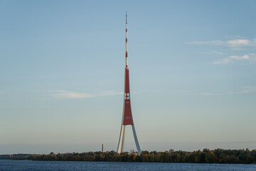 View of Riga TV tower on Zaķusala island surrounded by water and trees, iconic broadcasting...