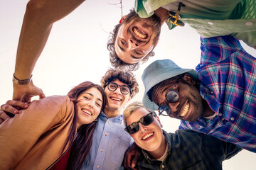Low angle view of happy diverse friends in a huddle looking down at camera. Friendship, community...