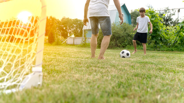 Grandfather and grandson play football in the summer cottage