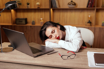 Tired businesswoman sleeping at desk with laptop illustrating burnout and overtime