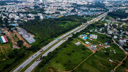 Fototapeta premium Arial shot of Beautiful road infrastructure of karnataka in India. Aerial view city traffic Highway road with car vehicle movement in Bangalore.