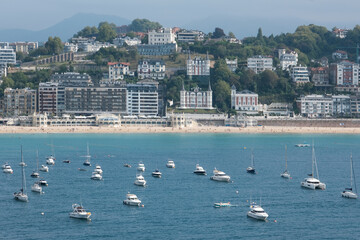 View of San Sebastian (Donostia) town, La Concha Beach and yachts in La Concha Bay on sunny summer day. Gipuzkoa, Basque Country, Spain.