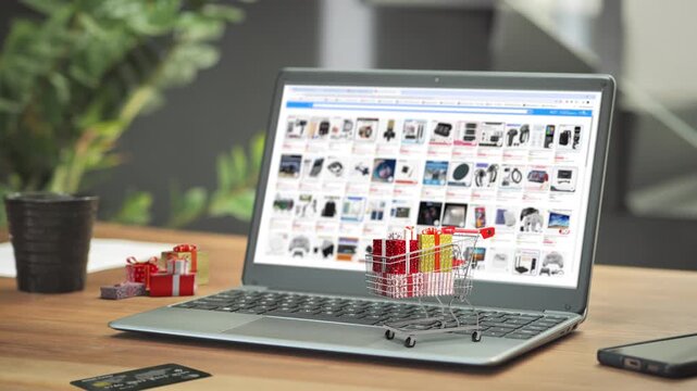 laptop computer on the wooden table with 3d shopping cart full of christmas gifts and credit card on the desk,online purchase e-commerce concept