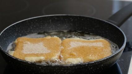 Golden-brown food being fried in a pan with oil. It appears to be a snack or dish in preparation. Cooking in a kitchen setting: Plze?, Czech - Oct,11,2025