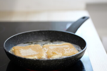Frying food in a pan with oil. Close-up view of the cooking process with visible bubbles and golden-brown surface: Plze?, Czech - Oct,11,2025