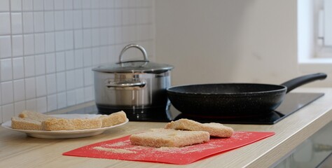 Cooked food on a red mat, next to a plate and a pan on a kitchen countertop. The food appears to be prepared for a meal: Plze?, Czech - Oct,11,2025