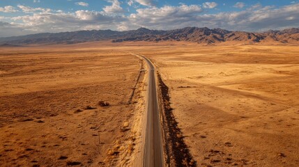 A lonely road stretches across a vast, arid desert landscape toward distant mountains