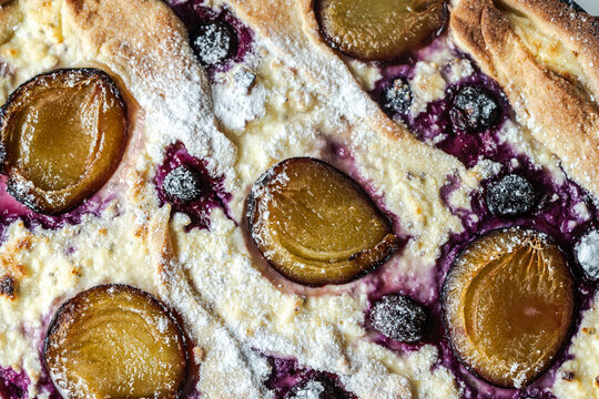 Close-up: cheesecake, quiche or tart with blueberries and prunes. View from above.
