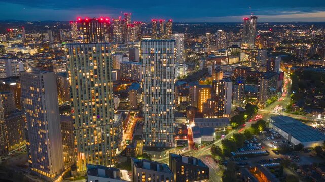 Dynamic aerial hyperlapse moving left to right across Salford area, revealing Manchester&rsquo;s illuminated skyline and Trinity Way traffic.