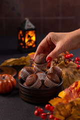 Hand picking chocolate muffins for halloween autumn celebration