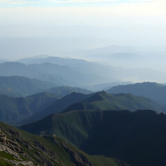 Breathtaking mountain landscape with rolling hills and misty valleys under a soft blue sky
