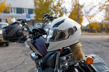 Closeup of a White Motorcycle Helmet with Fur Tail on Handlebars against Autumn Background