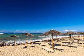 Idyllic Beach Scene with Straw Umbrellas and Sunbeds on a Sunny Day, Greek island of Lefkada