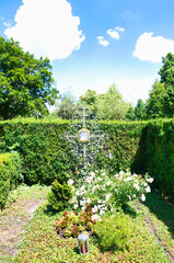 Familiengrabstelle zwischen Hecken und einem schönen Eisenkreuz auf einem Münchner Friedhof © Blende8