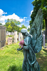 Schöner großer Engel mit frischen Blumen im Arm auf einem Münchner Friedhof © Blende8