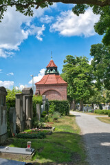 Weg über den Friedhof zu einem Mausoleum aus rotem Backstein  auf einem Münchner Friedhof © Blende8