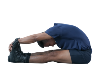 Man stretching forward touching toes, wearing blue shirt and shorts, performing seated hamstring stretch on floor, fitness and flexibility training, healthy lifestyle concept