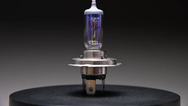 Halogen car bulb with H4 base. Rotates on a black background. Car bulb for lighting while driving.