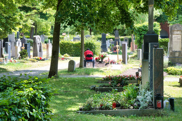 ein Besucher sitzt neben einem Grabhügel in stillem Gebet auf einem Münchner Friedhof © Blende8