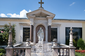 Wunderschönes großes reich verziertes Familiengrab einer angesehenen Familie mit Säulen und einer großen Mariendarstellung und einem Eisentor auf einem Friedhof in Rosenheim  © Blende8