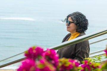 A woman is sitting on a railing overlooking the ocean