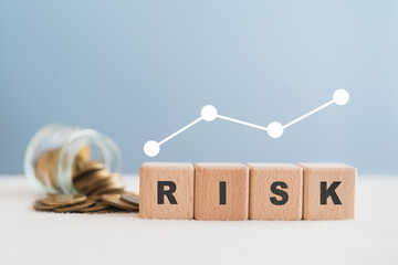 for financial risk assess management and business analysis concept. RISK text on wooden cube blocks with blurred coins and white graph