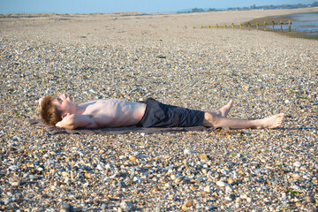 Teenage Boy Sunbathing On A Beach