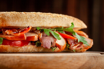 Smoked meat ciabatta sandwich with arugula and tomato