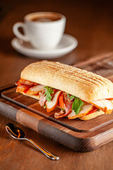 Breakfast ciabatta sandwich with smoked meat and coffee